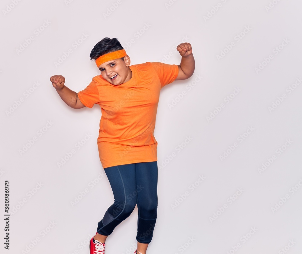 Adorable hispanic kid wearing sportswear smiling happy. Jumping with smile on face over isolated white background
