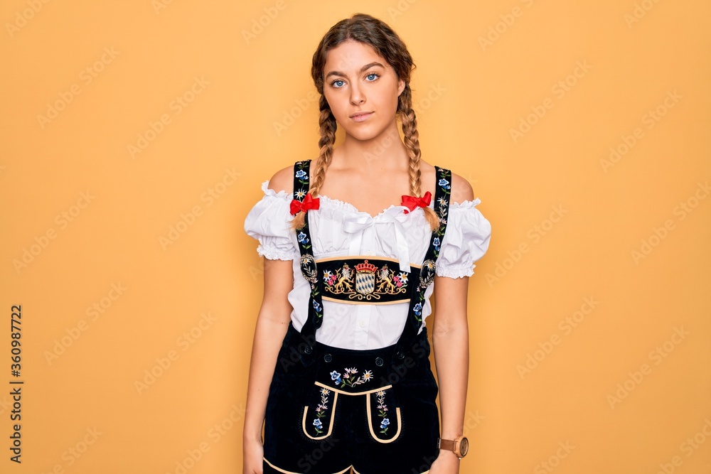Young beautiful blonde german woman with blue eyes wearing traditional octoberfest dress Relaxed with serious expression on face. Simple and natural looking at the camera. Young beautiful blonde german woman with blue eyes wearing traditional octoberfest dress Relaxed with serious expression on face. Simple and natural looking at the camera.