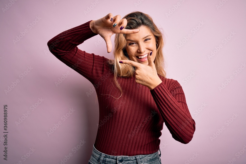 Young beautiful blonde woman wearing casual sweater over isolated pink background smiling making frame with hands and fingers with happy face. Creativity and photography concept.