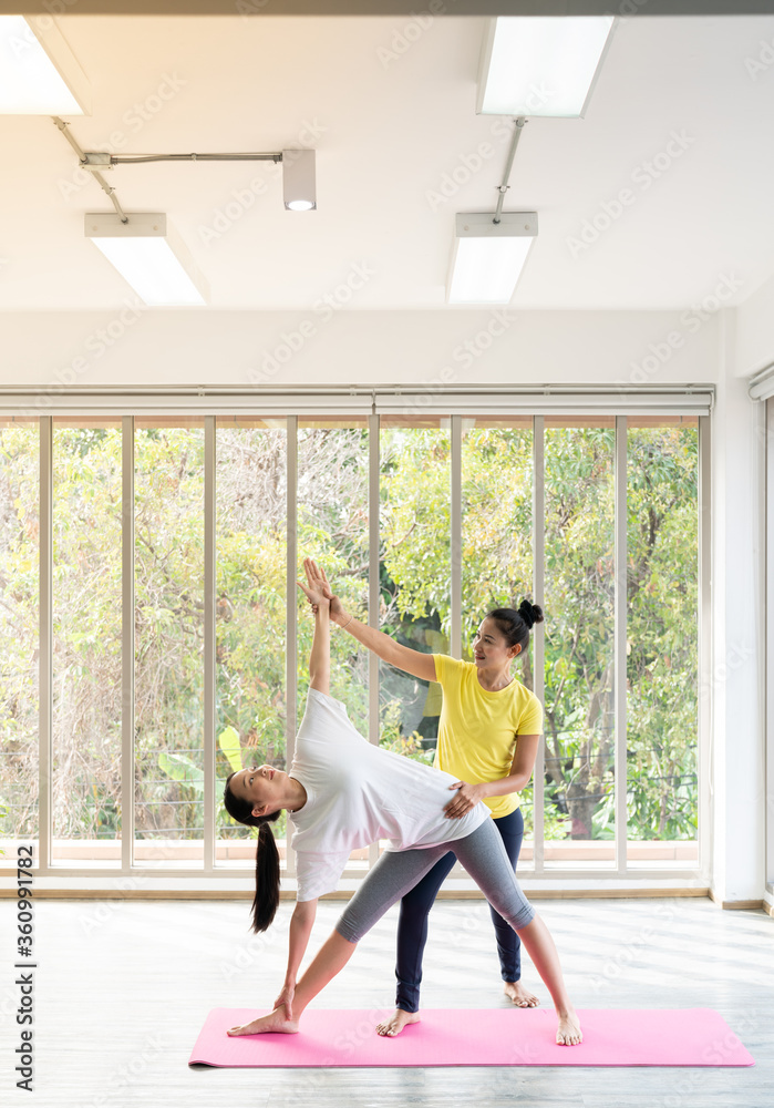 Two happy asian women in yoga poses in yoga studio with natural light setting scene / exercise concept / yoga practice / copy space / yoga studio