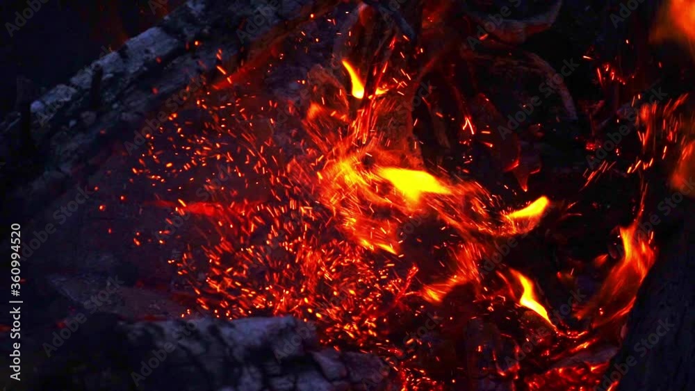 Slow motion of an open pit fire being stoked with a burning log. Slow motion of an open pit fire being stoked with a burning log.