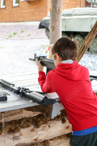 Canvastavla young boy with a machine gun in the outdoor shooting gallery