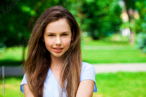 Portrait of a young beautiful brunette girl in summer park
