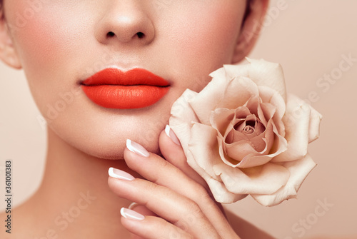 Beautiful model with a rose. Perfect woman face makeup close up. Lipstick. Beautiful nails