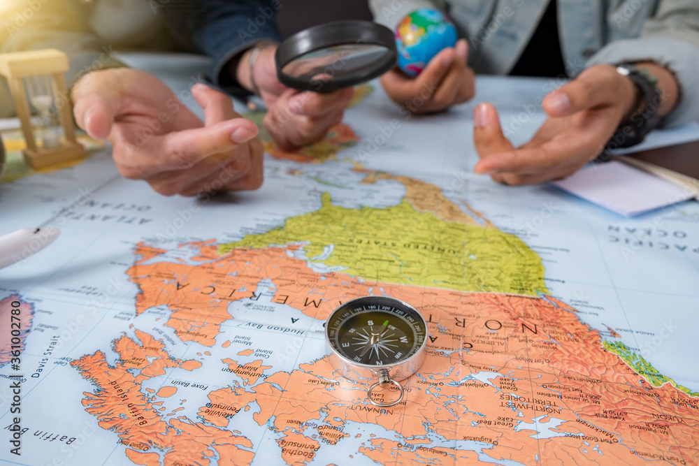 Young woman planning vacation using world map and compass along with other travel accessories. Tourist wearing brown hat looking Young woman planning vacation using world map and compass along with other travel accessories. Tourist wearing brown hat looking