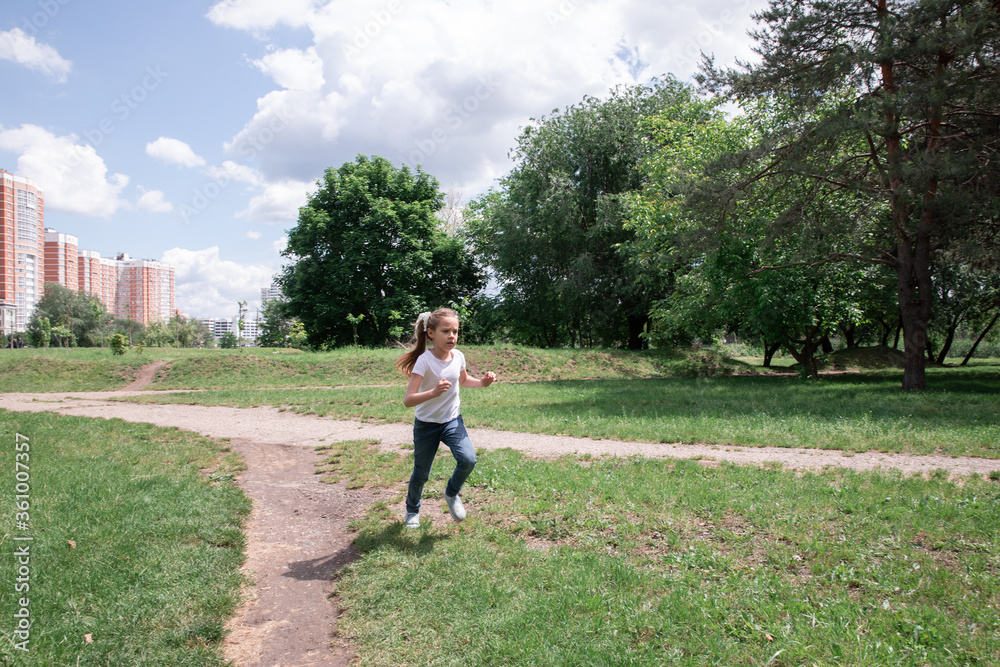 Young little girl runs through a green park. the child runs Young little girl runs through a green park. the child runs
