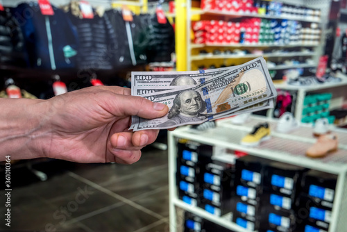 male hand holding dollar in clothing store for purchase