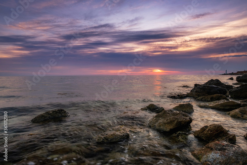Dramatic sunset over beach with a natural pond in the foreground. © YURII Seleznov