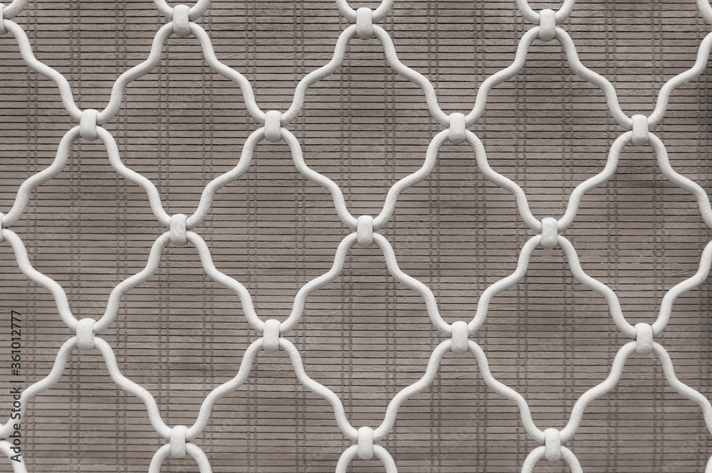 Naklejka premium Diamond shape of white curved wrought iron steel on the lattice window, gray bamboo curtain background, lattice work for house decoration