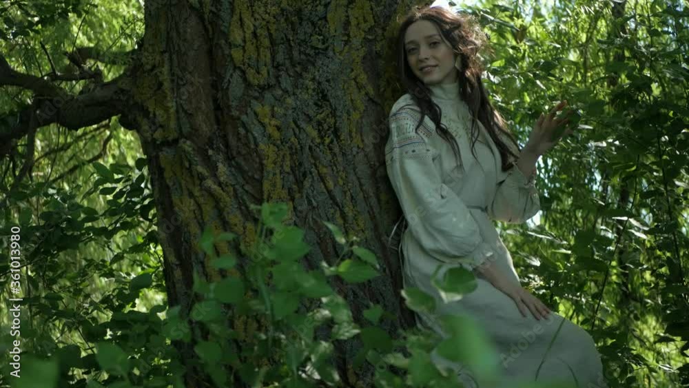 A girl dressed in an old dress stands on the river bank. Beautiful woman standing near a willow tree. Young girl walks in nature alone. Summer nature. A girl dressed in an old dress stands on the river bank. Beautiful woman standing near a willow tree. Young girl walks in nature alone. Summer nature.