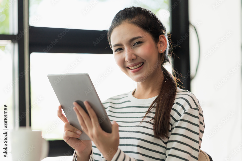 Asian woman using tablet. Smiling pretty woman sitting and work from home.