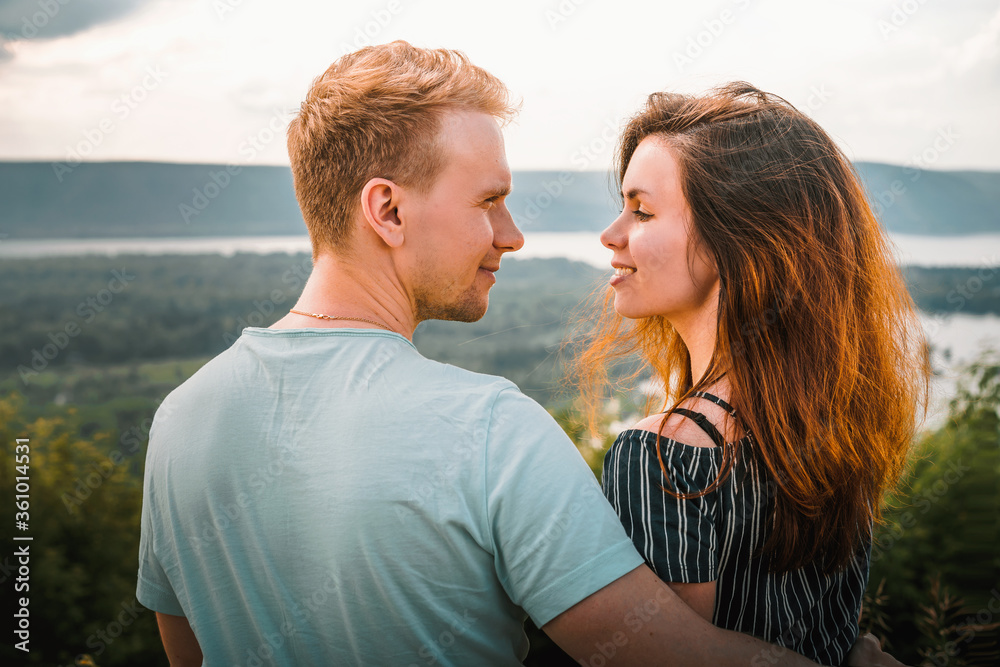 A man and a woman look at each other in love sitting on the edge of a mountain with a panorama of Russian nature with the Volga river and Islands A man and a woman look at each other in love sitting on the edge of a mountain with a panorama of Russian nature with the Volga river and Islands
