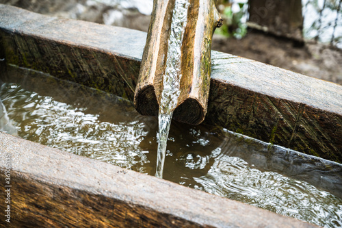 A closeup shop of clean, fresh, natural spring of drinking water falling from a wooden channel