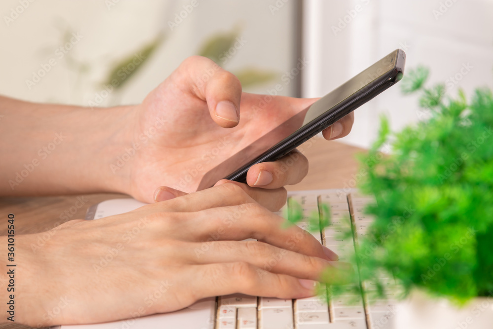 close-up of hands with mobile phone and computer