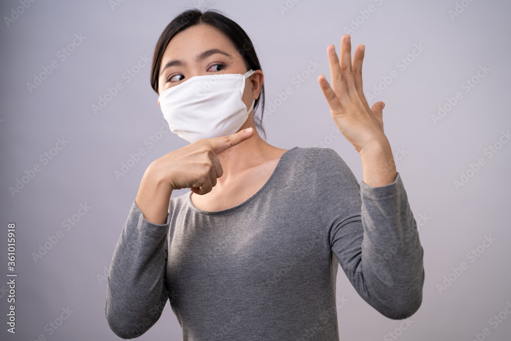 Don't Touch Your Face. Asian woman wearing protective face mask showing hand making stop sign standing isolated on background. Don't Touch Your Face. Asian woman wearing protective face mask showing hand making stop sign standing isolated on background.