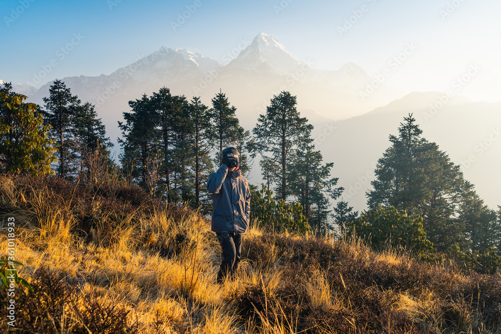 Young Asian man trekker taking picture from Poon hill view point in Annapurna base camp trekking route, Himalaya mountains range in Nepal