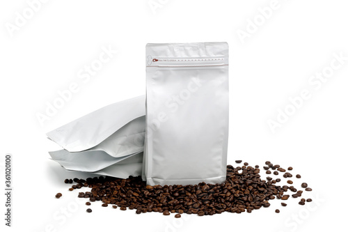 Mock-up plastic paper bag lying at coffee beans isolated on white background. Aluminium coffee package. Packaging template mockup.  