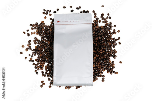 Mock-up plastic paper bag lying at coffee beans isolated on white background. Aluminium coffee package. Packaging template mockup.  