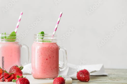 Mason jars of tasty strawberry smoothie on table