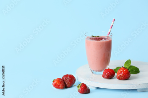 Glass of tasty strawberry smoothie on color background