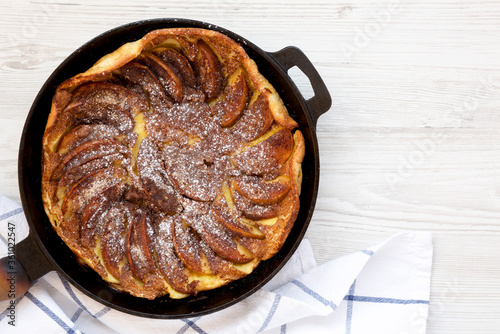 Homemade Apple Dutch Pannekoek Pancake in a cast-iron pan on a white wooden background, top view. Overhead, from above, flat lay. Copy space. photo