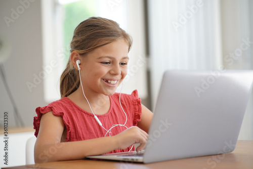 Young blond girl with red shirt connected with laptop at home