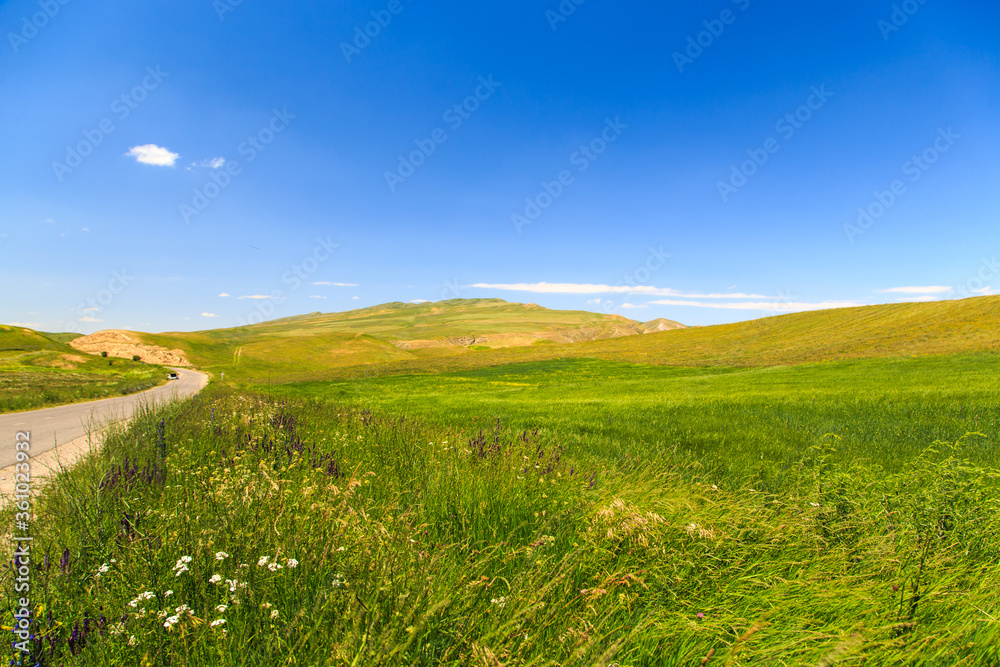 Beautiful spring and summer landscape. Mountain country road among green hills.