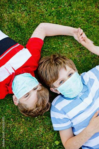 Two kids boys in medical mask as protection against pandemic coronavirus disease. Children, lovely siblings and best friends using protective equipment as fight against covid 19.