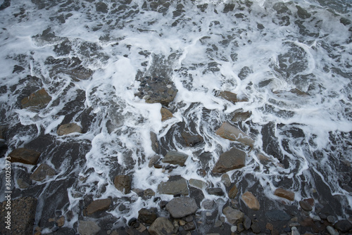 Top view of the sea wave and rocks. The water forms a whimsical pattern. Background, texture.