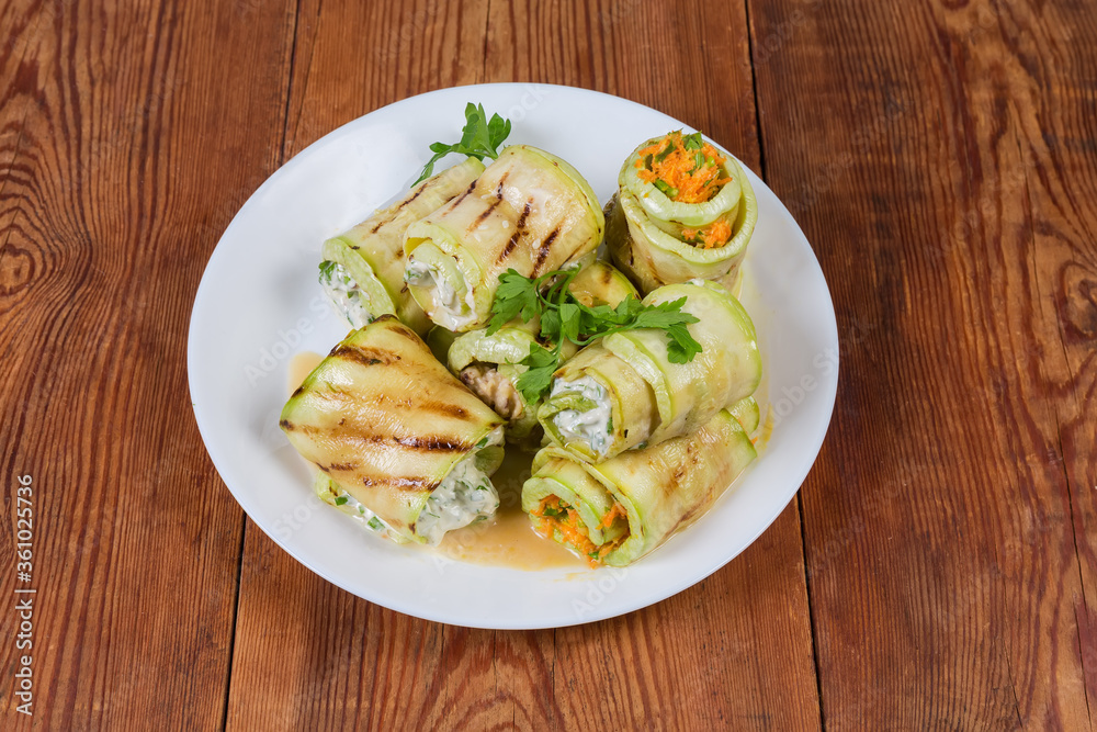 Zucchini rolls with different filling on dish on rustic table Zucchini rolls with different filling on dish on rustic table