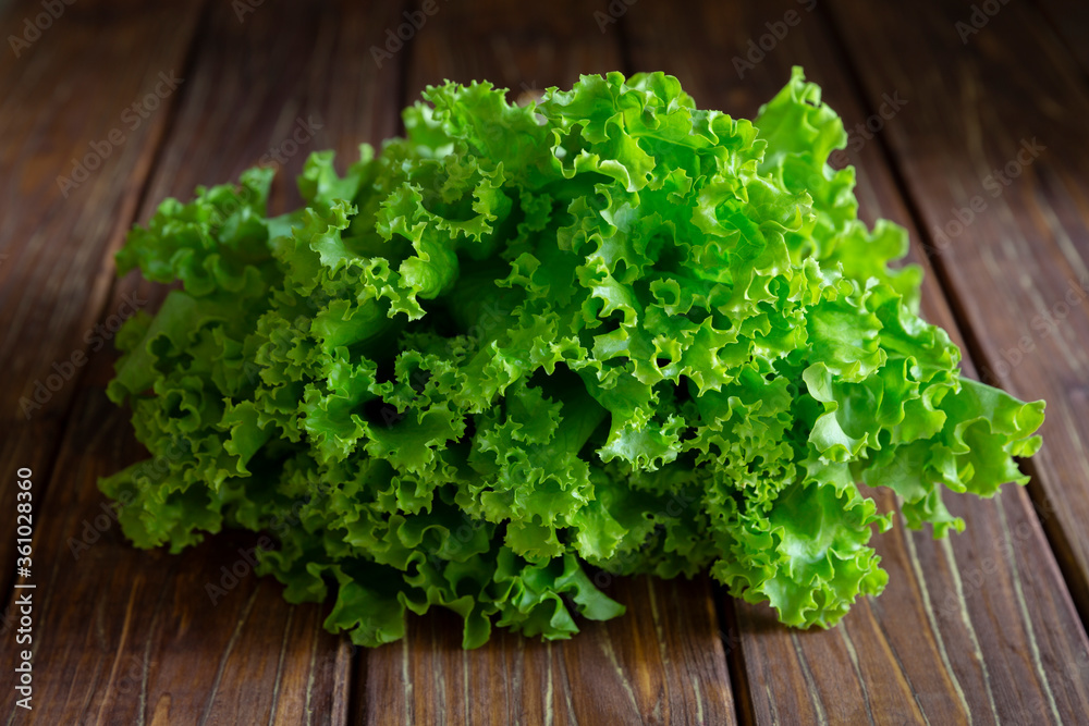 Green fresh lettuce leaves on wooden brown background. Green fresh lettuce leaves on wooden brown background.