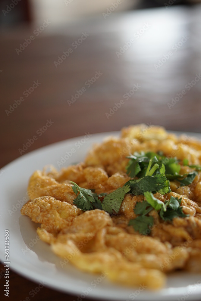 Angle view of Omelet top with coriander on wood table.(Thai style) Angle view of Omelet top with coriander on wood table.(Thai style)