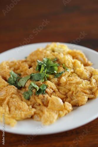 Angle of Omelet and top with coriander on wood table.(Thai style)