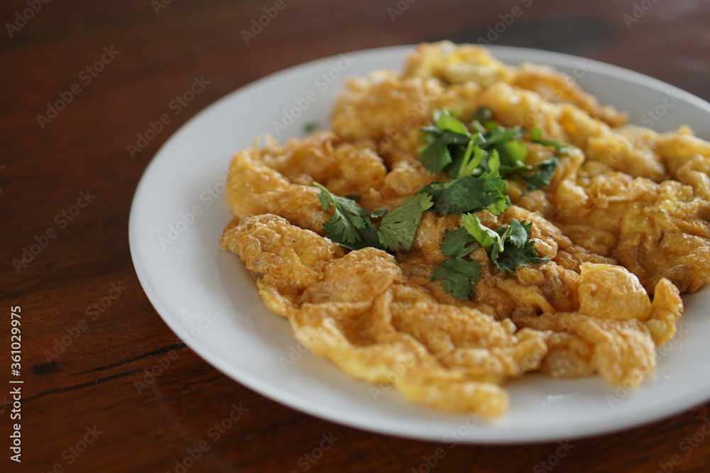 Angle view of Omelet top with coriander on wood table.(Thai style) Angle view of Omelet top with coriander on wood table.(Thai style)