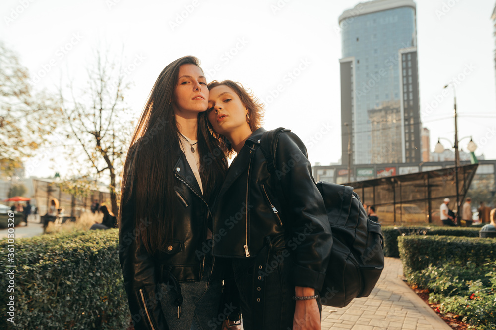 Φωτογραφία Street photo of attractive girlfriends at sunset, posing on camera, wearing casual clothes