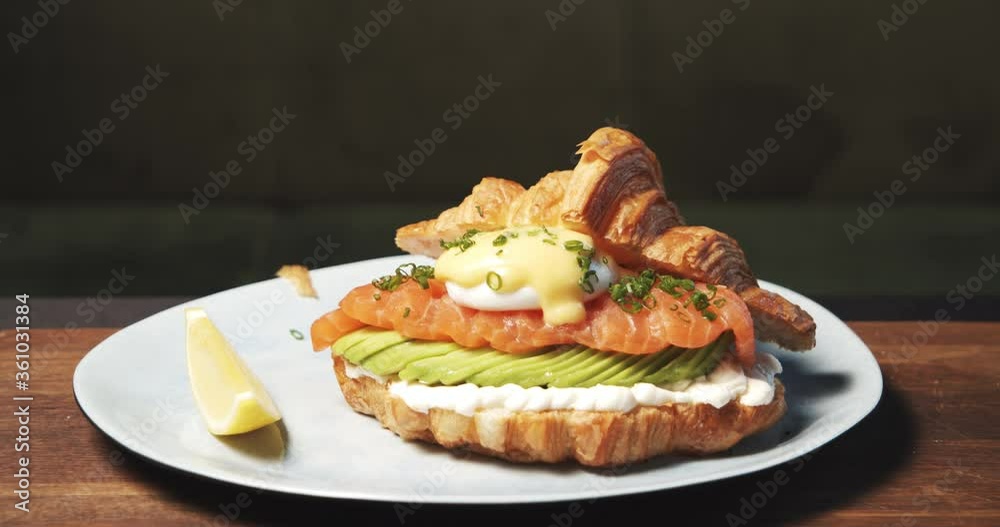 Closeup of delicious croissant with soft cheese, avocado, salmon fillet and egg benedict. Tasty and healthy breakfast. Closeup of delicious croissant with soft cheese, avocado, salmon fillet and egg benedict. Tasty and healthy breakfast.