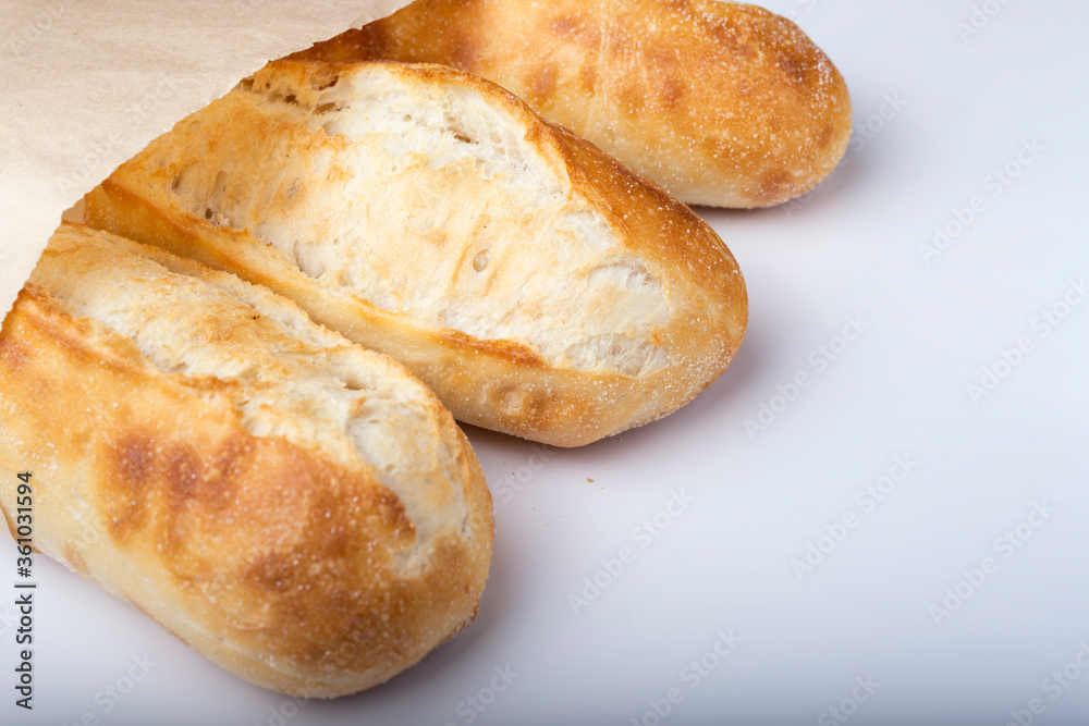 French bread rolls in the paper bag isolated on light background.