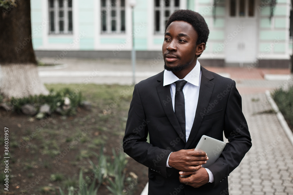 Close up horizontal portrait of young handsome african american sales manager. Male with tablet pc working in small business. Man using gadgets to manage a company. Copy space. Close up horizontal portrait of young handsome african american sales manager. Male with tablet pc working in small business. Man using gadgets to manage a company. Copy space.