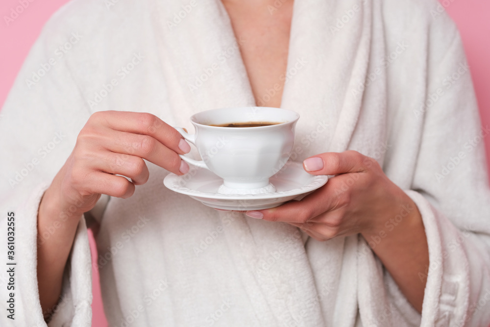 Coffe mood. Woman in white bath robe is holding a cup of coffee. Studio shoot on pink background. Coffe mood. Woman in white bath robe is holding a cup of coffee. Studio shoot on pink background.