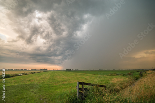 Thunderstorm over green meadows in Holland during sunset