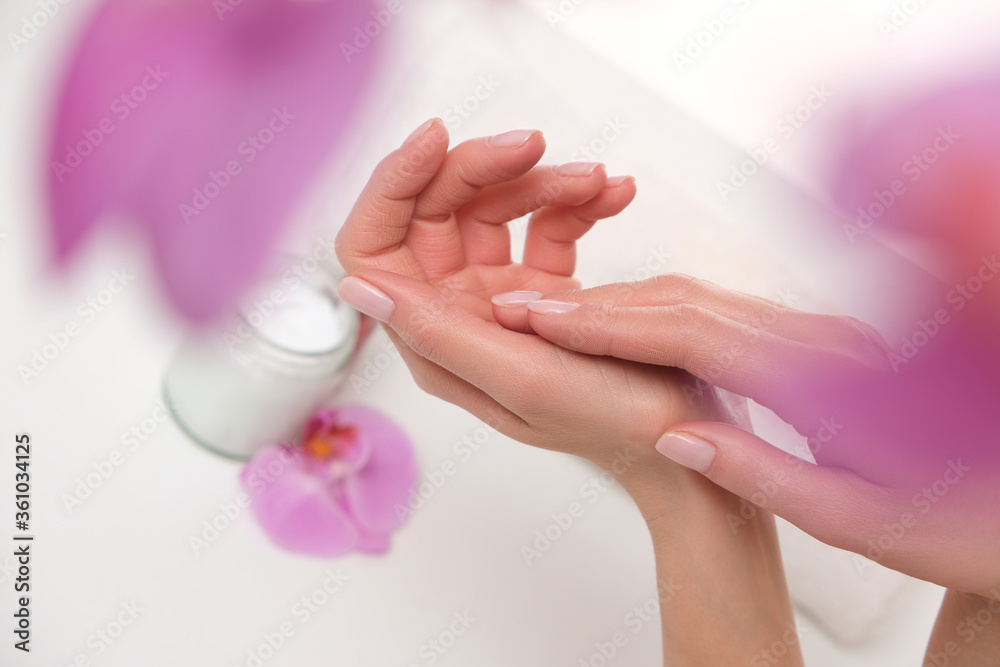 Naklejka premium Female hands in spa. Close up to pretty done manicure. Orchid mood.