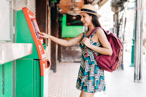 Fotografía Young brunette girl traveler withdrawing money from ATM in Thailand, Asia