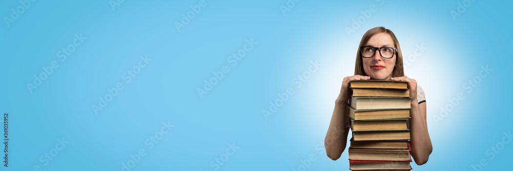 Young girl in a white dress and sunglasses put hands on a pile of books on a blue background. Concept of Education and Reading of books. Banner. Copy space Young girl in a white dress and sunglasses put hands on a pile of books on a blue background. Concept of Education and Reading of books. Banner. Copy space