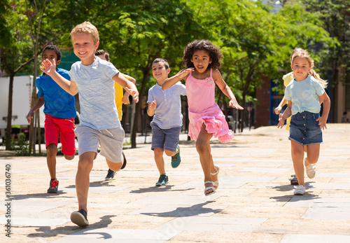 Group of joyful children running down the summer street
