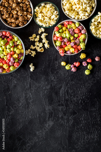 Set of flavored popcorn and soda on black desk top-down space for text