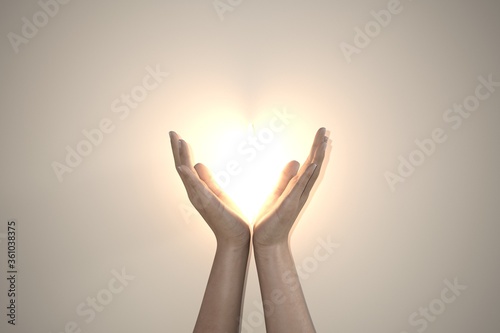 Praying hands hold a crucifix or cross of metal necklace with faith in religion and belief in God on confession background. Power of hope or love and devotion cuore luce sole photo