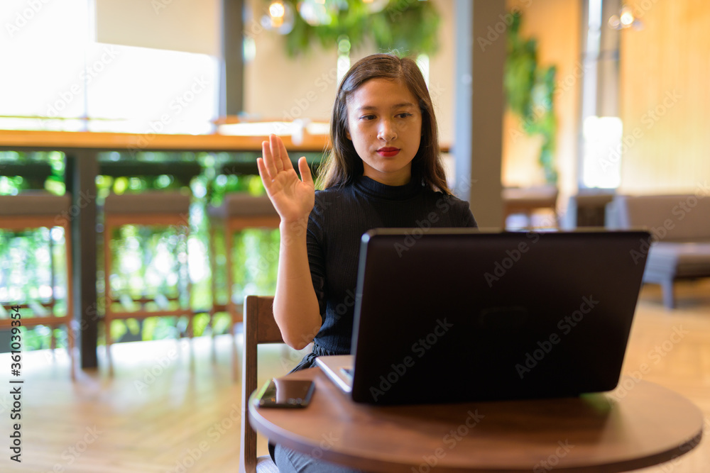 Φωτογραφία Young beautiful Asian businesswoman video calling with laptop at the coffee shop