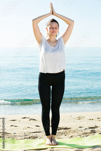 Adult woman in white T-shirt is staying and practicing asana