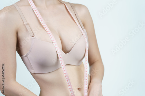 Foto Woman measuring her chest for breast implant surgery.