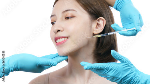 Hands of beautician injecting Botulinum toxin type A to asian woman in jaw area.